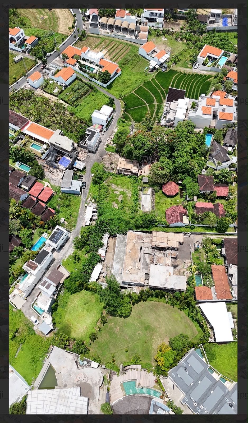 Aerial context view showing rice fields and villa developments around the parcel