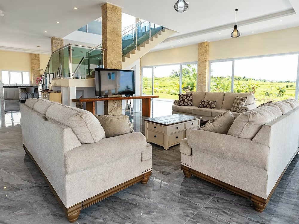 Open-plan lounge with marble floors and rice field views