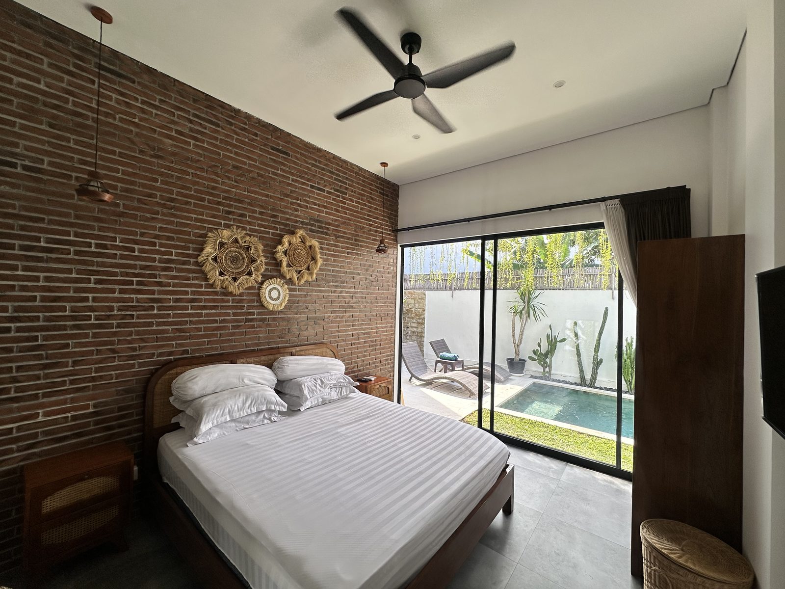 Bedroom with brick feature wall opening to the pool