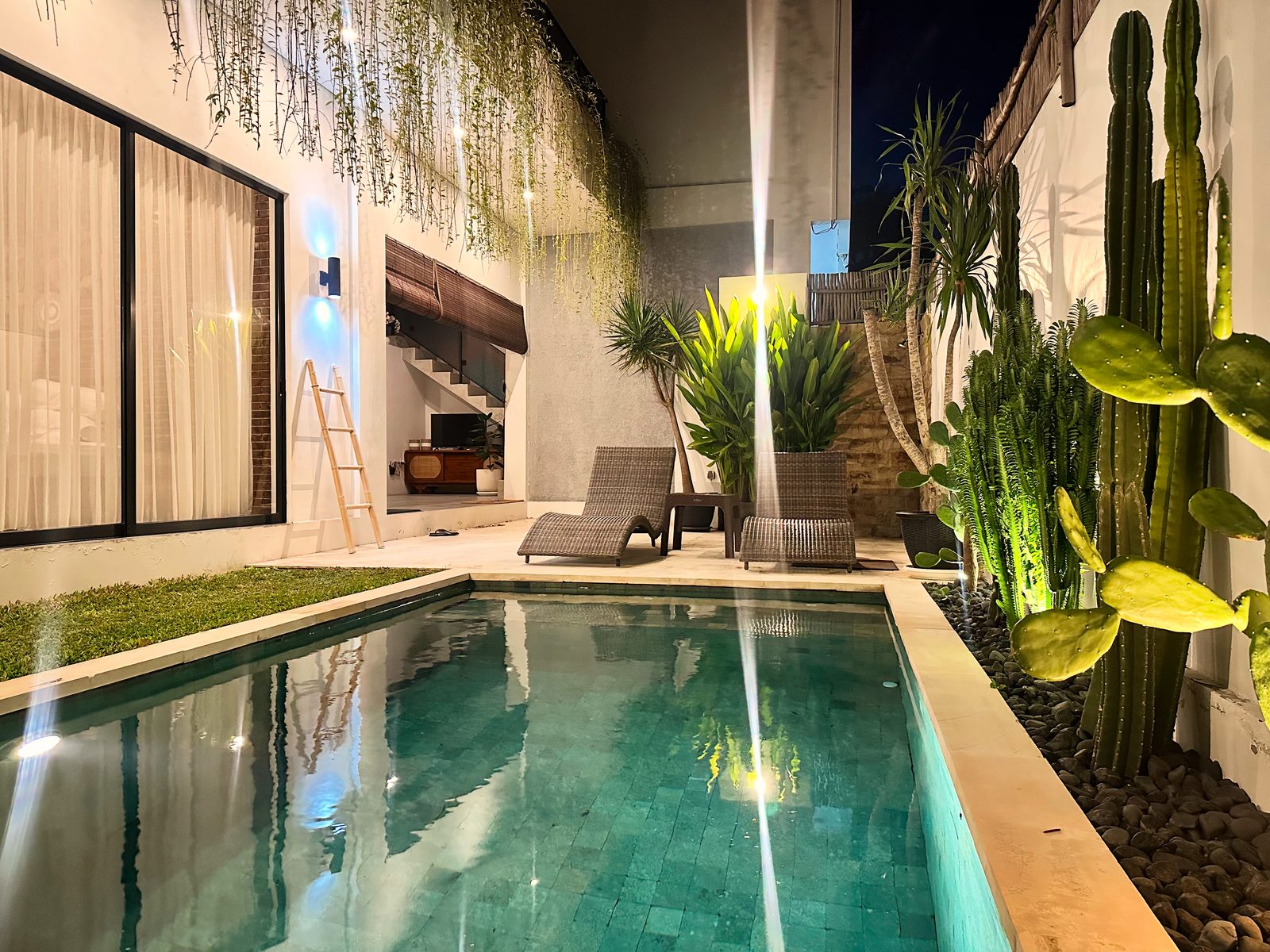 Private pool illuminated at night with tropical garden